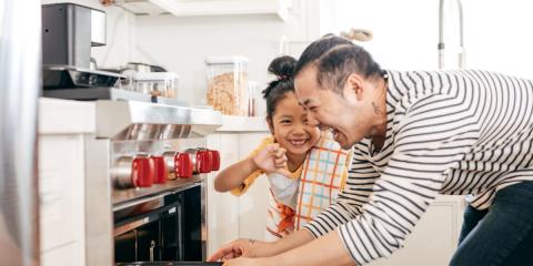 Dad and daughter putting biscuits into the oven