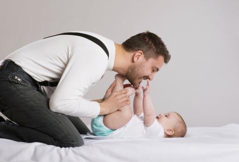 Dad smiling at baby while changing their nappy