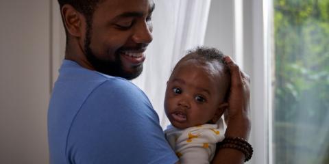 Father holding baby, smiling