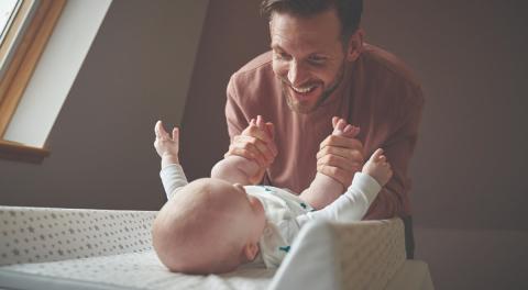 Photo of a dad smiling down at his baby on the changing mat 