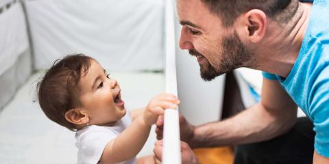 Dad smiling at baby in cot