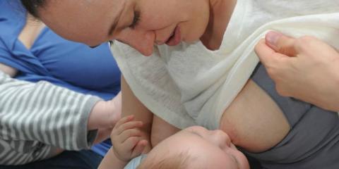 Photo of a mother lifting her shirt to breastfeed her baby