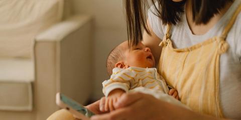 Mum holding sleeping baby making a phone call on her mobile