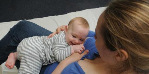 Image of a mum cradling a smiling baby in her arms.