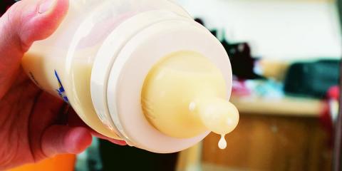 Photo of someone dripping milk from a baby bottle