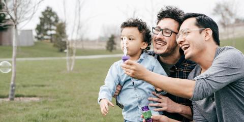 Dads and toddler blowing bubbles in the park