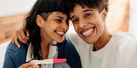 Same sex couple smiling at the results of a pregnancy test