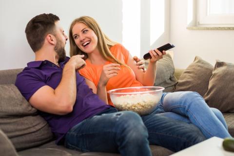 Happy couple on sofa eating popcorn together