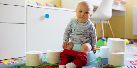 Image of a toddler smiling and siting on a potty.