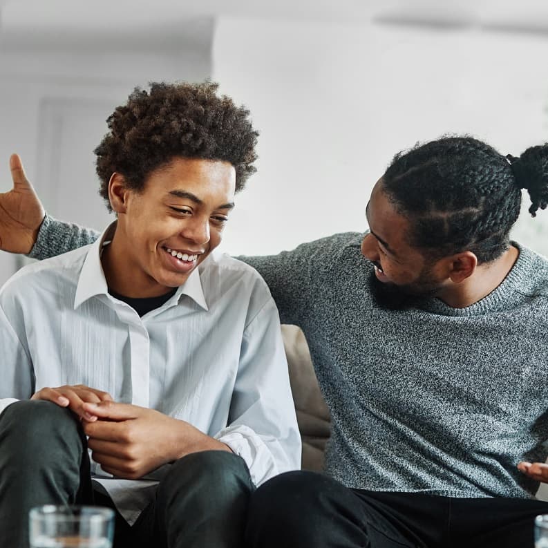 Teen boy and dad chatting and laughing together