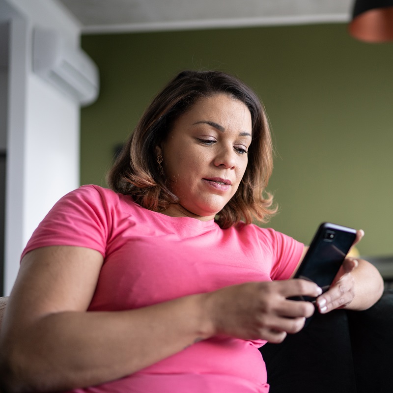 Woman wearing a pink top looking at her phone